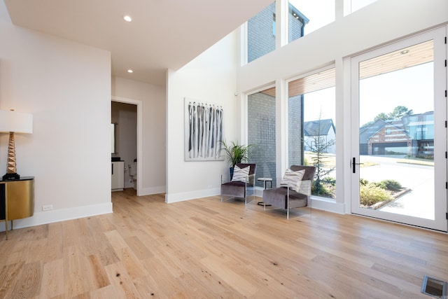 living area featuring a high ceiling and light hardwood / wood-style floors