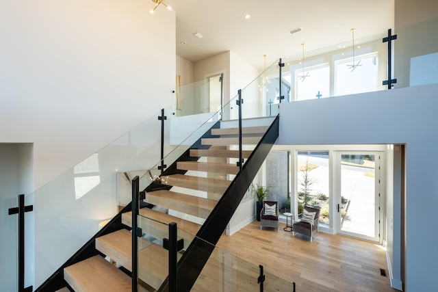 stairs with hardwood / wood-style floors and a high ceiling