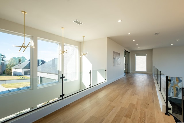 spare room with a notable chandelier and light wood-type flooring