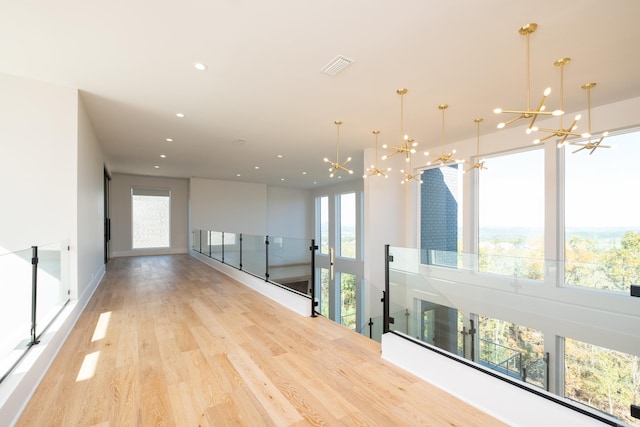 hallway with light hardwood / wood-style floors and a chandelier