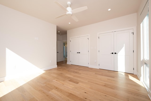 unfurnished bedroom with two closets, light hardwood / wood-style flooring, and ceiling fan