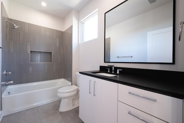 full bathroom with tile patterned flooring, tiled shower / bath, vanity, and toilet