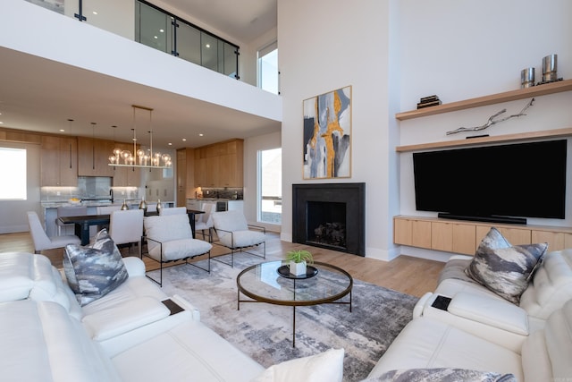 living room with a high ceiling, an inviting chandelier, and light hardwood / wood-style floors