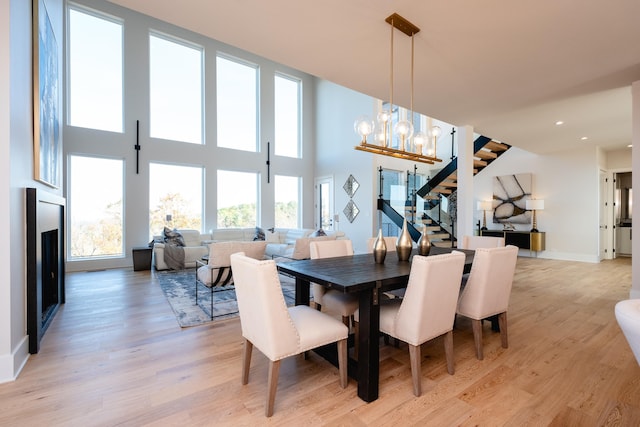 dining room featuring light hardwood / wood-style floors, a chandelier, and a high ceiling