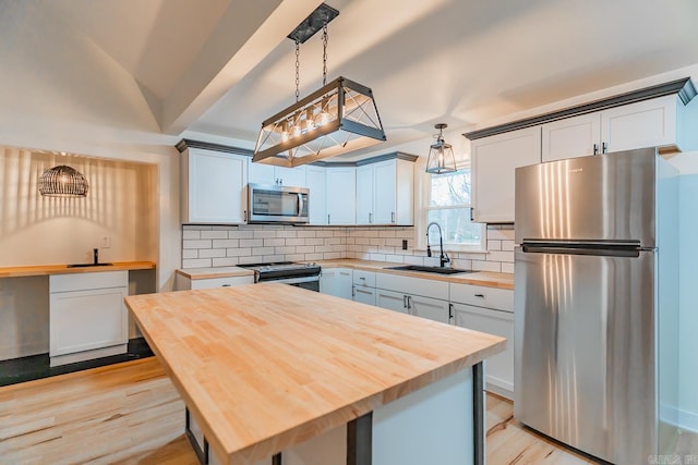 kitchen with stainless steel appliances, sink, butcher block countertops, and decorative light fixtures