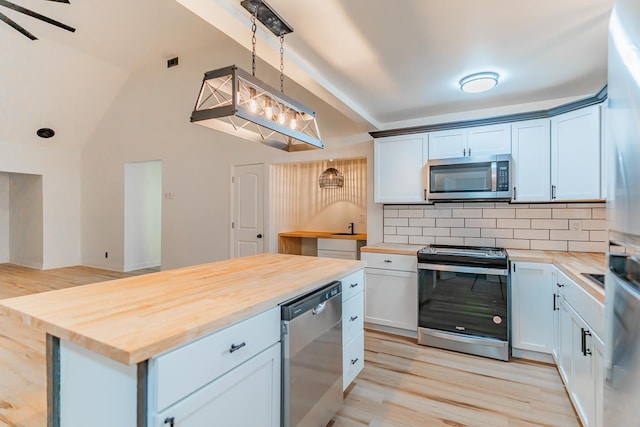 kitchen with butcher block counters, hanging light fixtures, stainless steel appliances, white cabinets, and light wood-type flooring