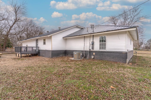 view of side of property with a wooden deck, a lawn, and cooling unit