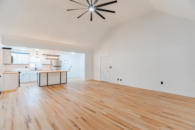 unfurnished living room featuring sink, light hardwood / wood-style flooring, and high vaulted ceiling