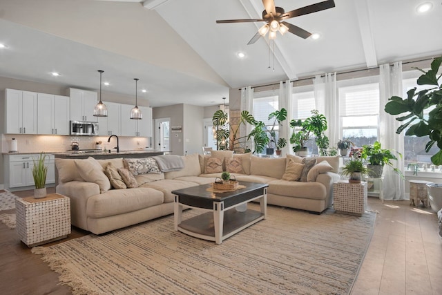 living room with high vaulted ceiling, sink, beam ceiling, and light hardwood / wood-style flooring