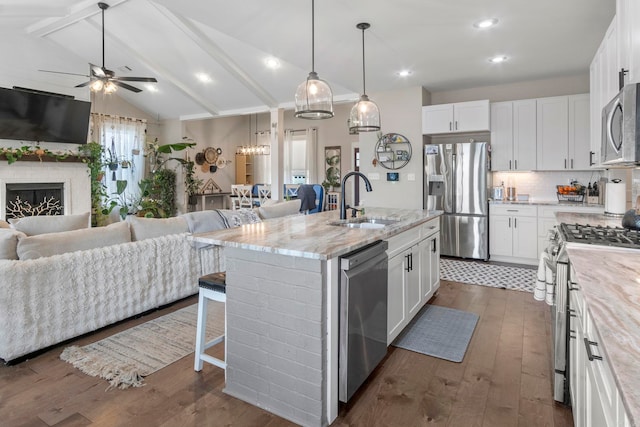 kitchen with stainless steel appliances, an island with sink, sink, and white cabinets