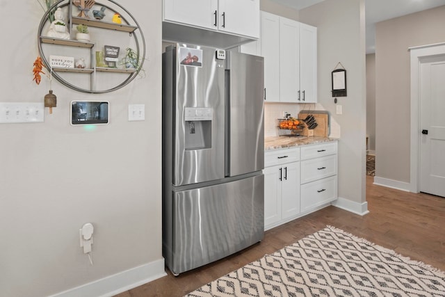 kitchen with white cabinetry, stainless steel refrigerator with ice dispenser, backsplash, and light stone counters