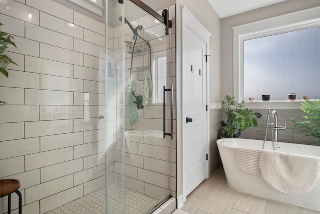 bathroom featuring tile walls and independent shower and bath