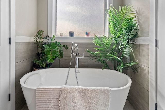 bathroom featuring sink, a bathtub, and tile walls