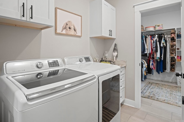 clothes washing area with cabinets, light tile patterned floors, and washing machine and clothes dryer