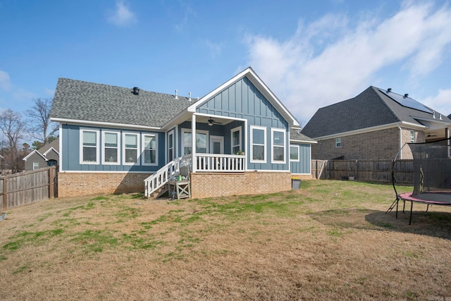 back of house featuring a yard and a trampoline