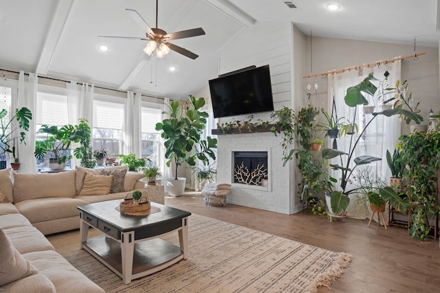 living room with lofted ceiling with beams, ceiling fan, hardwood / wood-style floors, and a fireplace