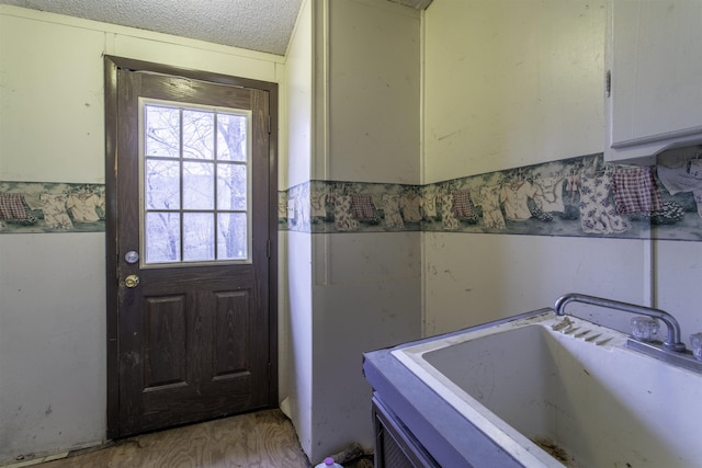 doorway featuring sink, a textured ceiling, and light hardwood / wood-style floors