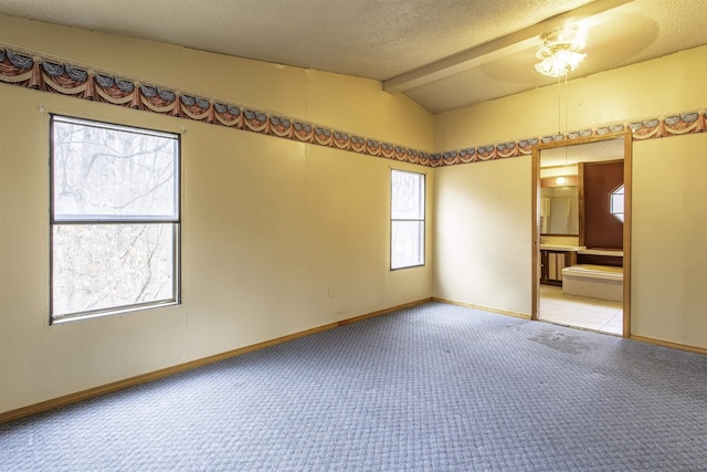 empty room with light colored carpet, a textured ceiling, and vaulted ceiling with beams