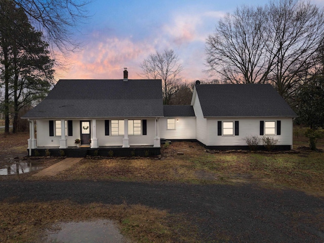 view of front of property featuring a shingled roof, a chimney, and a porch