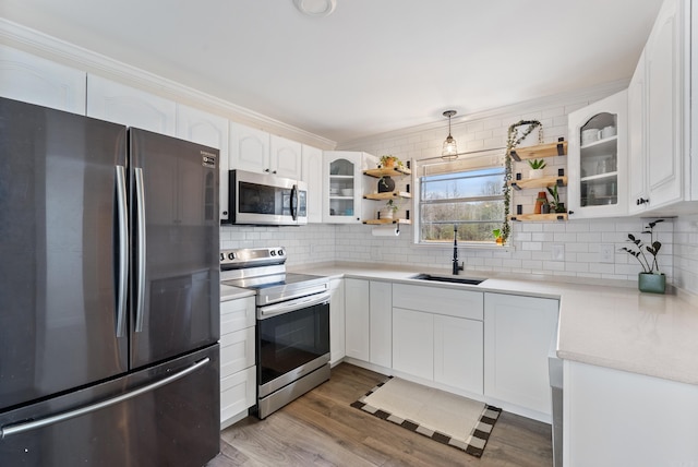 kitchen featuring white cabinetry, appliances with stainless steel finishes, sink, and decorative light fixtures