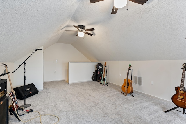 recreation room with ceiling fan, vaulted ceiling, light carpet, and a textured ceiling