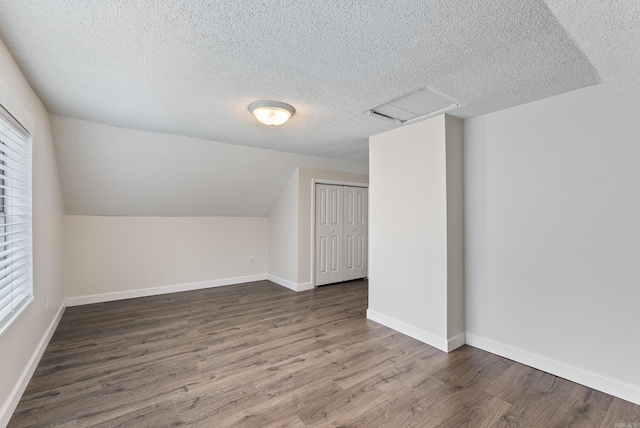 additional living space featuring lofted ceiling, hardwood / wood-style flooring, plenty of natural light, and a textured ceiling