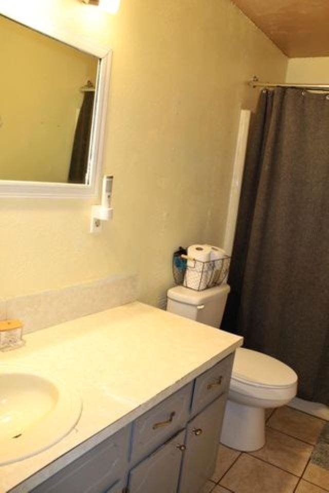 bathroom featuring vanity, walk in shower, tile patterned floors, and toilet