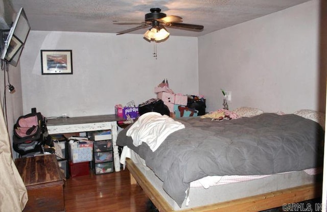 bedroom featuring ceiling fan, a textured ceiling, and dark hardwood / wood-style flooring