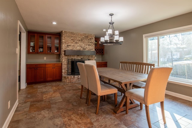 dining room featuring a brick fireplace, a wealth of natural light, and a chandelier