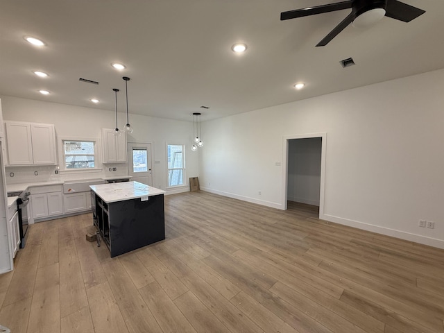 kitchen with decorative light fixtures, a center island, white cabinets, and light wood-type flooring