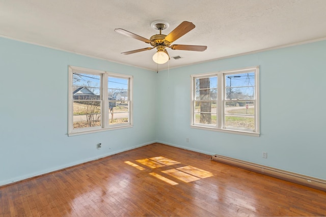 empty room with ceiling fan, a textured ceiling, a wealth of natural light, and wood-type flooring