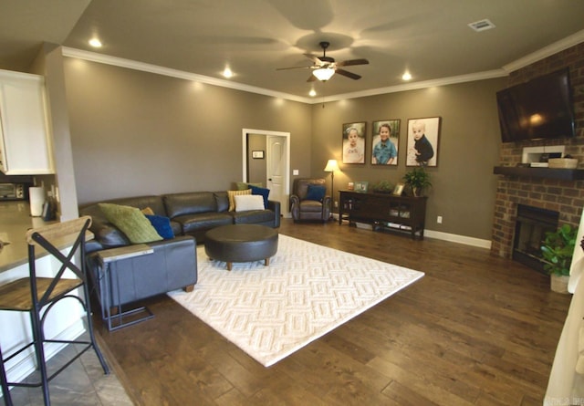 living room with ceiling fan, a fireplace, ornamental molding, and dark hardwood / wood-style flooring