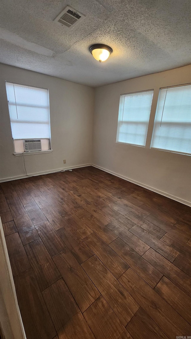 spare room with dark wood-type flooring, baseboards, and visible vents