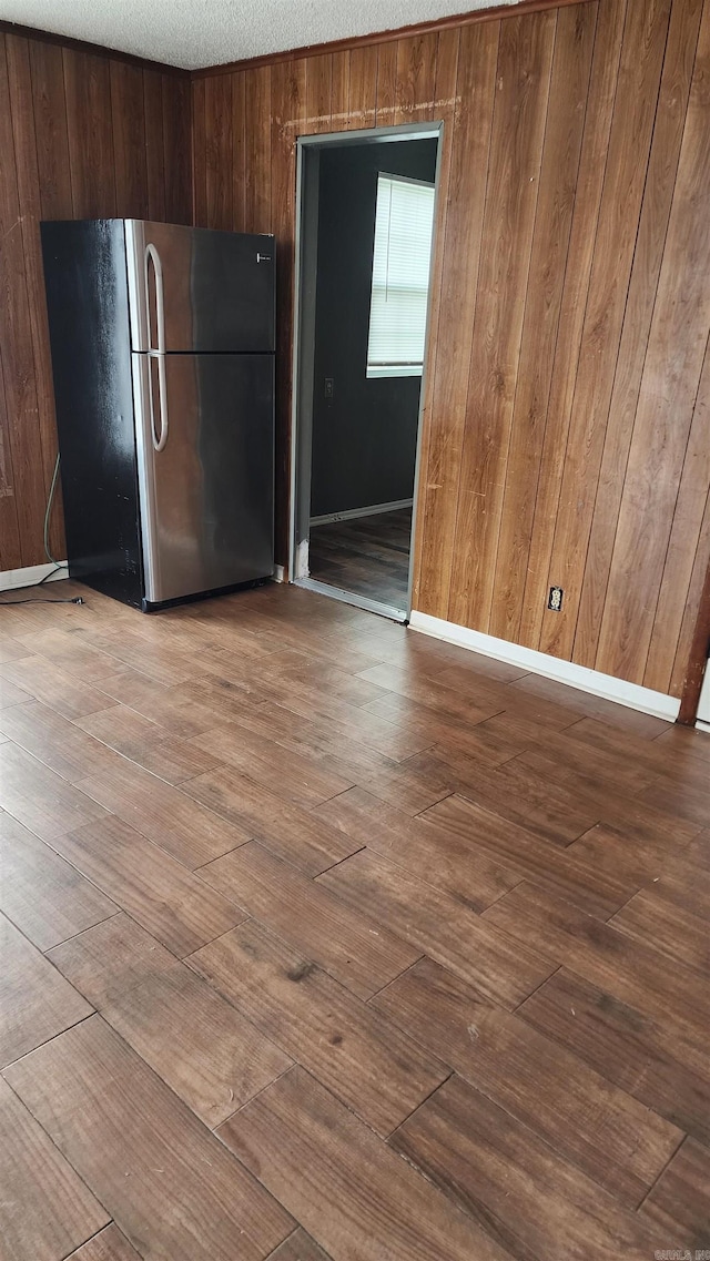 kitchen with freestanding refrigerator, wood walls, a textured ceiling, modern cabinets, and dark wood finished floors
