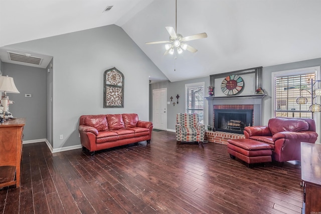 living room featuring a brick fireplace, dark wood-type flooring, and a healthy amount of sunlight