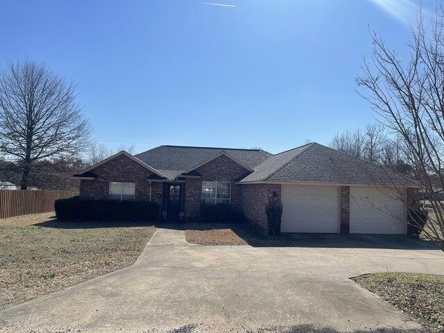 ranch-style home with a shingled roof, brick siding, and fence