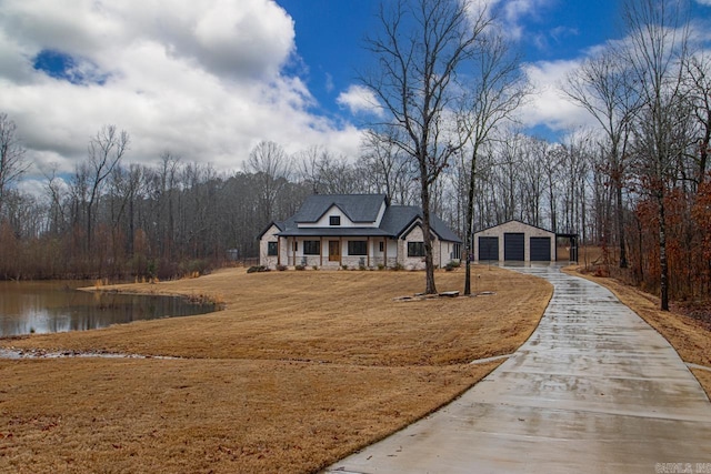 view of front of house with a garage, a water view, an outbuilding, and covered porch