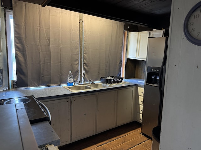 kitchen with stainless steel fridge, sink, white cabinets, and light wood-type flooring