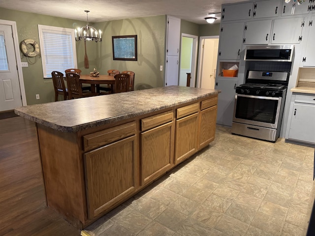 kitchen with appliances with stainless steel finishes, a center island, pendant lighting, and a notable chandelier