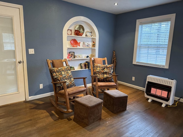 sitting room featuring heating unit, built in features, and dark hardwood / wood-style floors