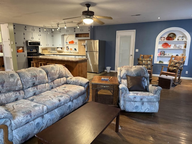 living room featuring sink, dark wood-type flooring, built in features, and ceiling fan