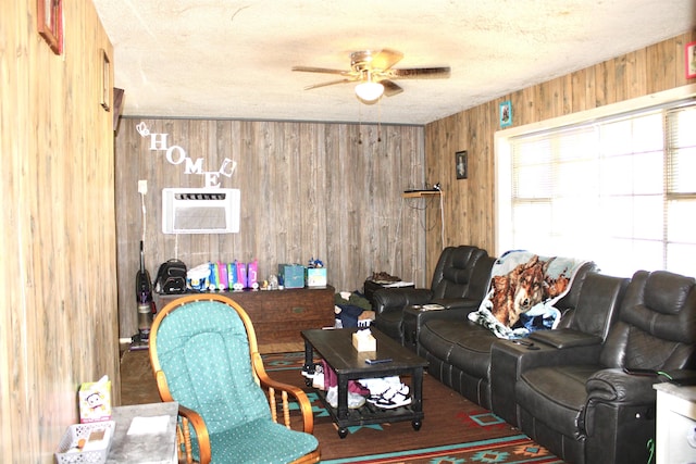 living room featuring a textured ceiling, an AC wall unit, ceiling fan, and wood walls