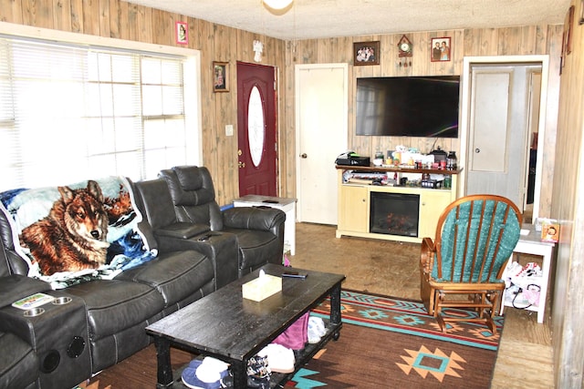 living room featuring a fireplace, wooden walls, and a textured ceiling