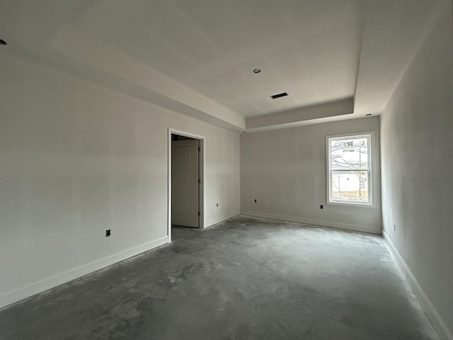 unfurnished room featuring a tray ceiling and concrete flooring