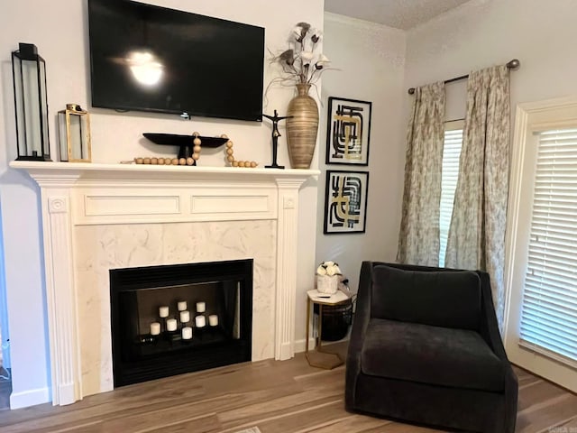 living area featuring a premium fireplace, hardwood / wood-style floors, and crown molding