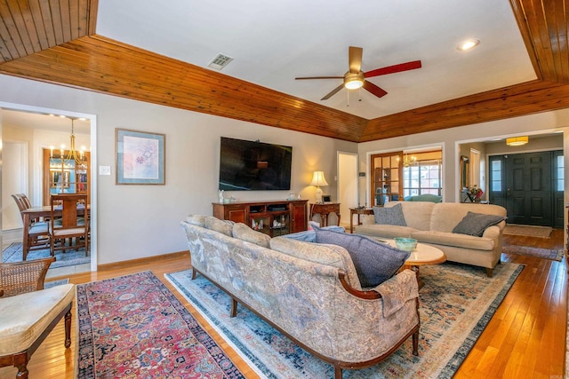 living room featuring lofted ceiling, wood-type flooring, wooden ceiling, a tray ceiling, and ceiling fan with notable chandelier