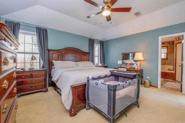 bedroom featuring ceiling fan, lofted ceiling, light carpet, and ensuite bath