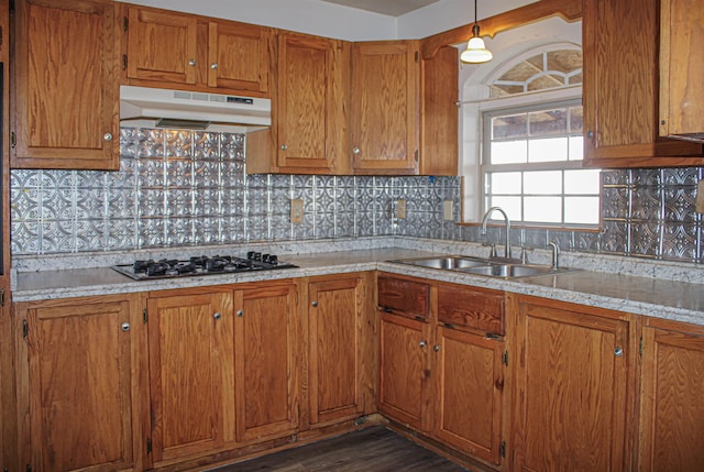 kitchen with dark hardwood / wood-style floors, decorative light fixtures, sink, backsplash, and stainless steel gas cooktop