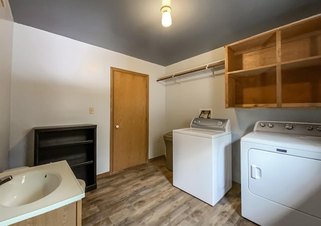 clothes washing area featuring sink, hardwood / wood-style flooring, and independent washer and dryer