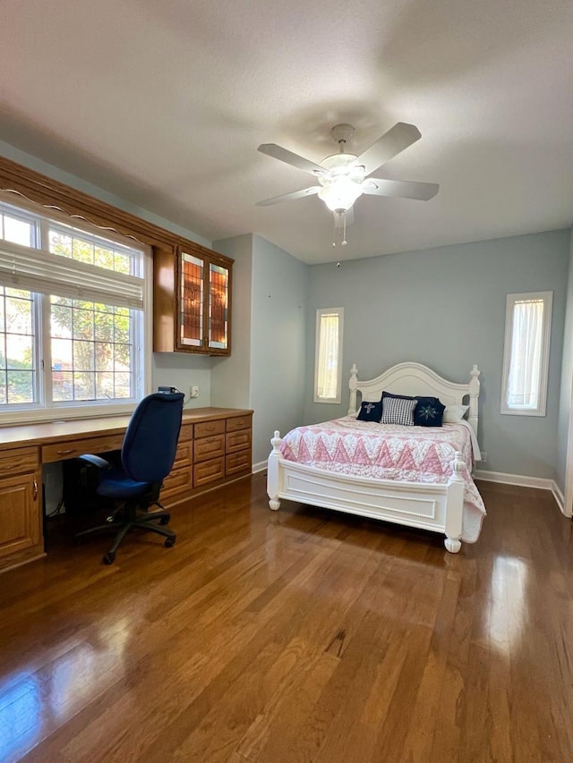 bedroom featuring dark hardwood / wood-style flooring, built in desk, and ceiling fan